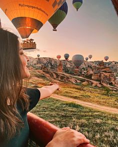 a woman looking at hot air balloons in the sky