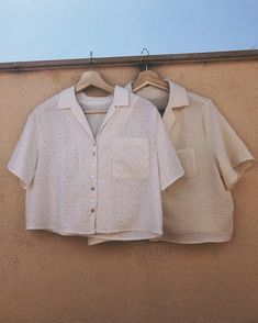 two shirts hanging on a clothes line against a tan wall with blue sky in the background