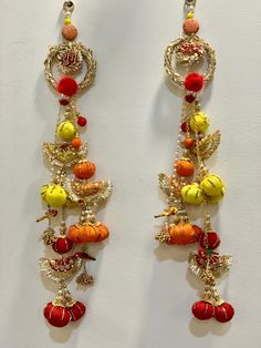 two pairs of dangling earrings with fruits and vegetables on them, hanging from the wall