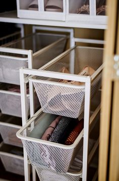 an organized closet with white mesh bins and drawers