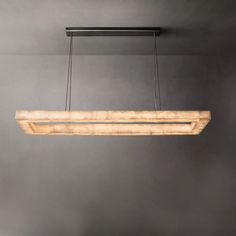 a wooden light fixture hanging from the ceiling in a room with grey walls and flooring