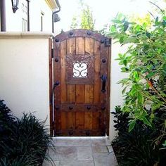 a wooden door is open on the side of a house in front of some plants