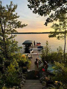 people are standing on the dock near boats and watercrafts at sunset or dawn