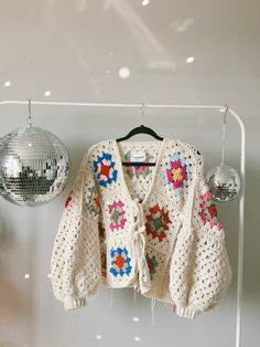 a crocheted sweater hanging on a rack next to disco ball ornament