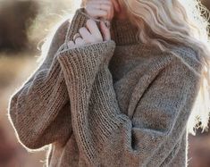 a woman with blonde hair wearing a brown sweater