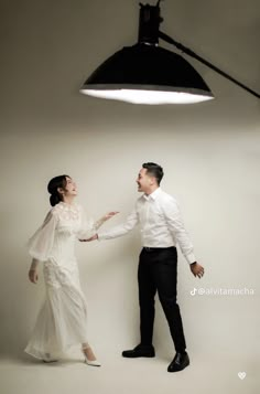 a man and woman standing next to each other in front of a black light fixture