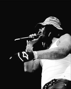 a black and white photo of a man with tattoos on his arm holding a microphone