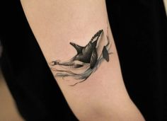 a woman's arm with a tattoo of an orca whale and waves on it