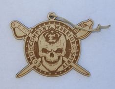 a wooden ornament with a skull and two crossed swords on the front is hanging from a cord