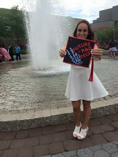 a woman holding up a sign in front of a fountain