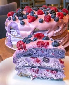 a piece of cake on a plate with raspberries and blueberries