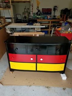 a black and red dresser with yellow stripes on the bottom is sitting in a garage