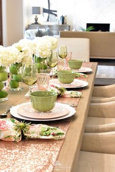 the table is set with green dishes and white flowers