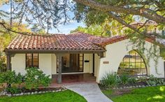 a white house with red tile roofing and green grass in front of the door