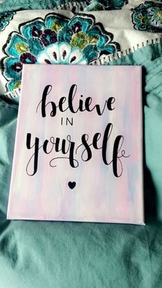 a wooden sign that says believe in yourself on top of a green bed with pillows