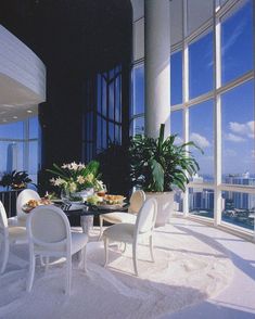 a dining room with large windows overlooking the cityscape and skyscrapers is pictured in this image