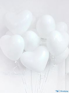 a bunch of white balloons in the shape of heart shaped balloons on a stick against a wall