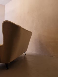 a tan couch sitting on top of a hard wood floor next to a white wall