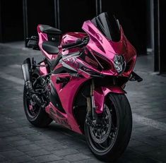 a pink motorcycle parked on top of a brick road