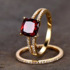 two gold rings with a red and white diamond ring sitting on top of each other