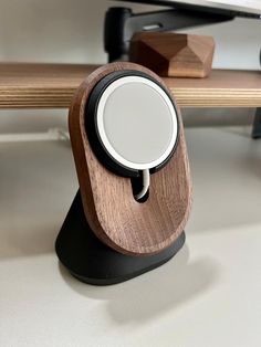 an electronic device with a wooden stand on top of a desk next to a keyboard