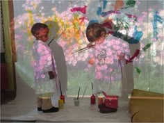 two children are painting flowers on a wall