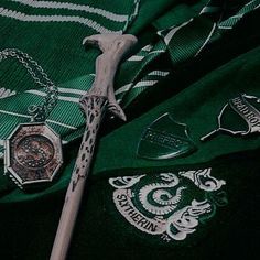 a green harry potter shirt with a wand, watch and necklace hanging from it's neck