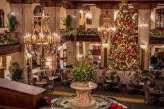 a christmas tree is in the middle of a room with chandeliers and tables