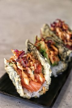 two pieces of sushi on a black plate