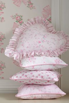 four pillows stacked on top of each other in front of a wallpapered background