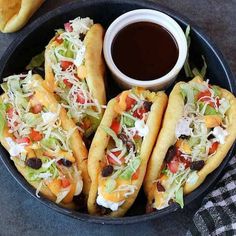 three hot dogs in buns with lettuce, tomatoes and other toppings