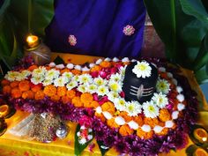 an arrangement of flowers and candles on a yellow table cloth with a black statue in the middle