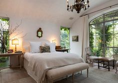 a bedroom with a large bed and chandelier hanging from it's ceiling