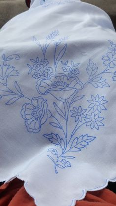 an embroidered piece of cloth with blue flowers on it sitting on top of a table