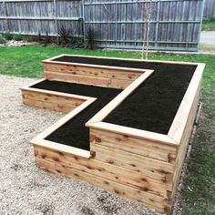 an outdoor garden with raised planters and gravel in the center, surrounded by grass