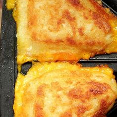 two pieces of cheese pizza sitting on top of a black grilling pan with melted cheese