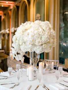 a table with white flowers and silverware is set for a formal dinner or reception