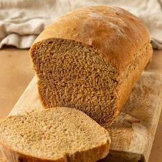 a loaf of bread sitting on top of a cutting board next to a slice of bread