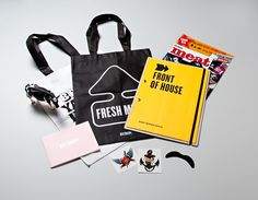 an assortment of personal items including a tote bag, magazine and other items are laid out on a table