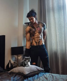 a shirtless man standing on top of a bed next to a cat