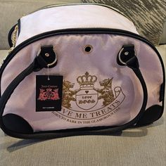 a pink purse with a crown on it sitting on a couch next to a pillow