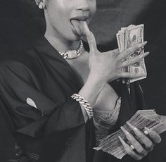 a black and white photo of a woman with money in her hand, making a funny face