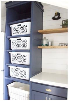 the shelves in this kitchen are painted blue and have white baskets on them, along with other items