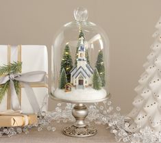 there is a snow globe with a house in it and presents under the glass dome