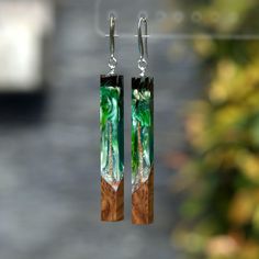 a pair of earrings with green and white designs hanging from it's ear wires