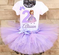 A stunning, glittery purple tutu embellished with a string of pearls is paired with a custom Sofia the First birthday shirt complete with your child's name and age. A coordinating bow is attached to the shirt as well. All tutus are made with high quality tulle and a 1" non-roll waist band. I make all my tutus very full and fluffy. I put as much tulle as I can possibly fit. The shirt is made with a professional heat press, NOT a home iron. Personalization is included at no additional cost. Please Princess Sofia Birthday, Tutu Size Chart, Heat Press Shirts, First Birthday Shirt, Purple Tutu, Birthday Tutu Outfit, First Birthday Outfit, First Birthday Shirts, Princess Sofia