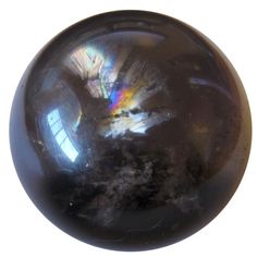 a black marble ball is shown against a white background with the reflection of a rainbow in it