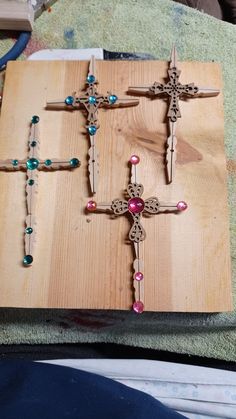 three wooden crosses with colored glass beads are on a table next to a towel and some other items