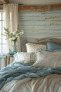 a bed with blue and white comforters in a bedroom next to a window,