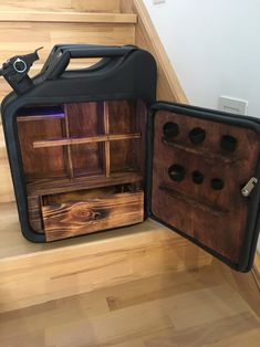 an open suitcase sitting on top of a wooden floor next to a stair case filled with bottles